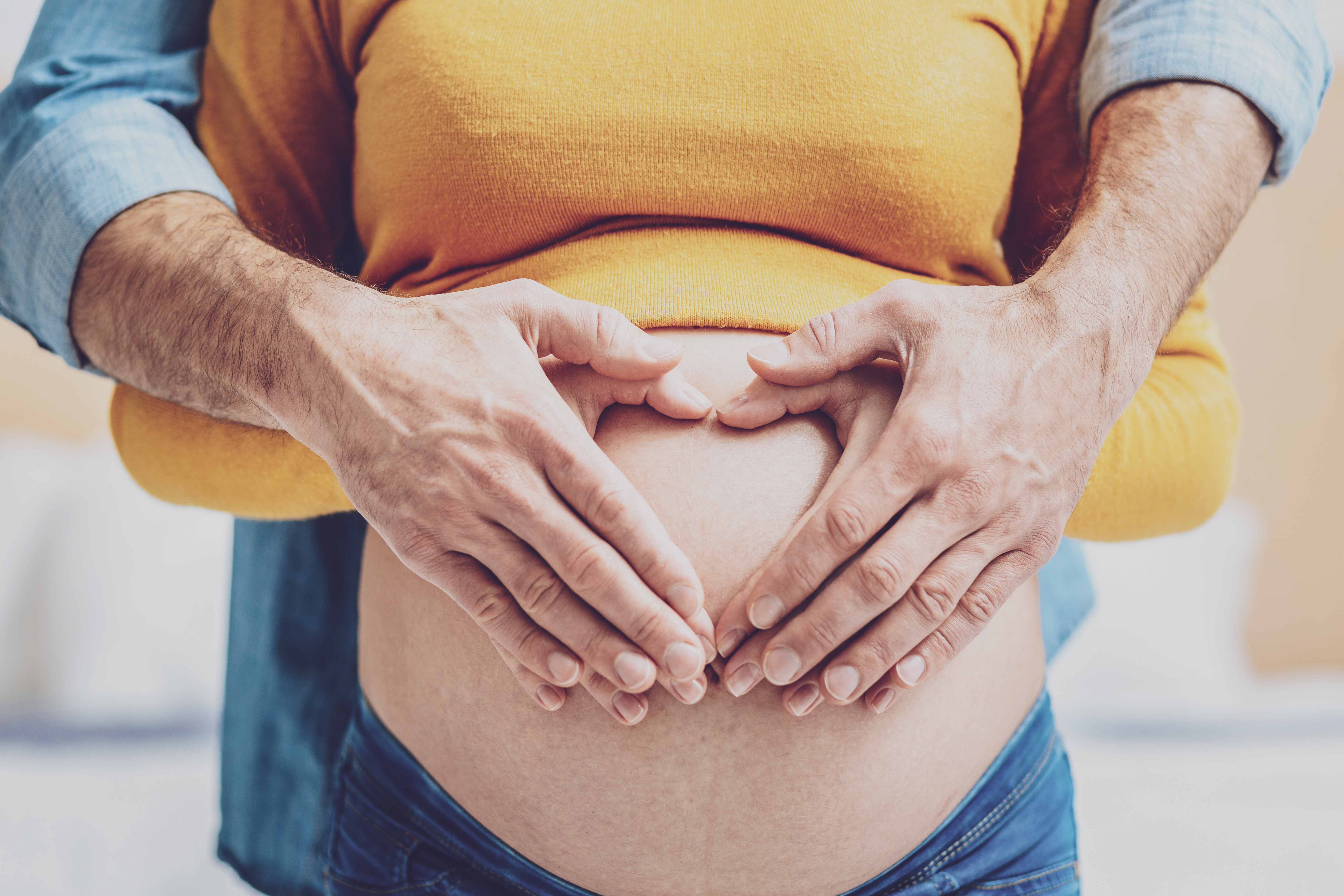 Mains d’un couple formant un cœur sur le ventre arrondi d’une femme enceinte, symbole d’amour, de soutien et de préparation à la parentalité dans le Valais central Mains d’un couple formant un cœur sur le ventre arrondi d’une femme enceinte, symbole d’amour, de soutien et de préparation à la parentalité dans le Valais central